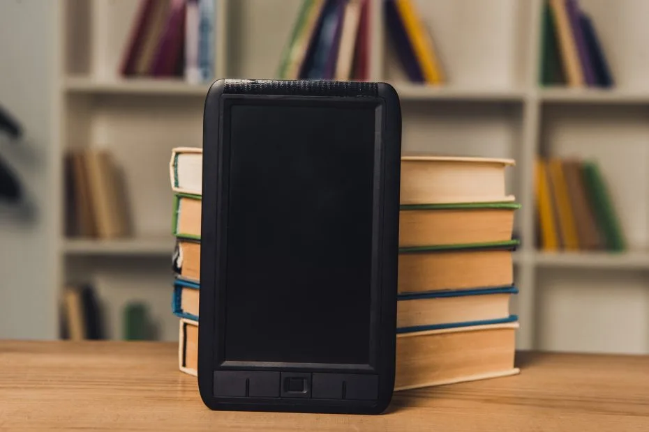 e-book with blank screen near paper books on table